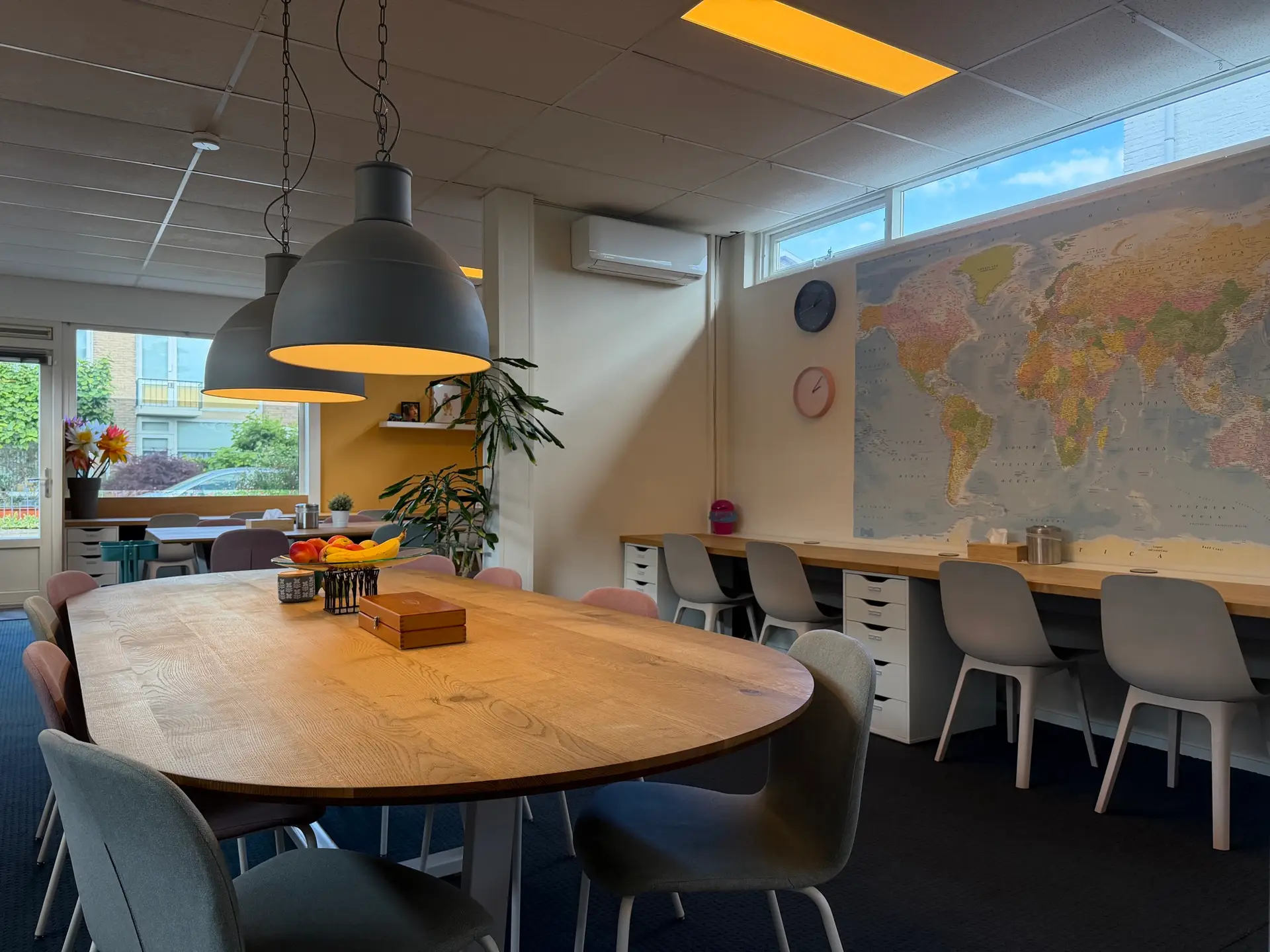 Overzicht van de grote werkruimte met werktafel, eigen werkplekken en wereldkaart bij Quadraat Zoetermeer